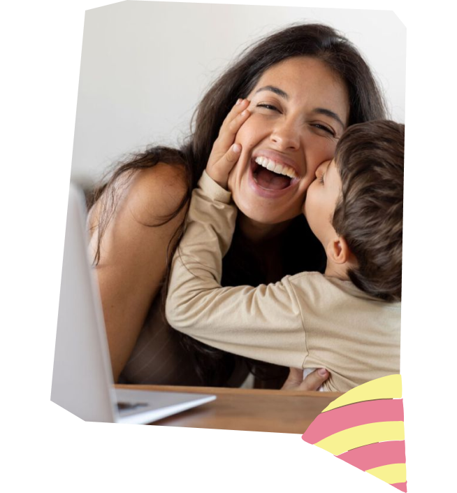 Mother laughing while her son kisses her cheek at a laptop